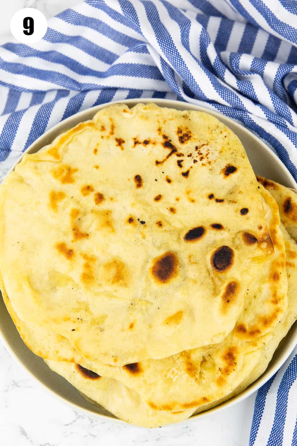 a stack of naan breads on a grey plate on a marble countertop 