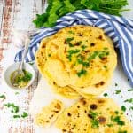 naan bread on a marble cutting board with a small bowl with melted butter, garlic, and parsley on the side