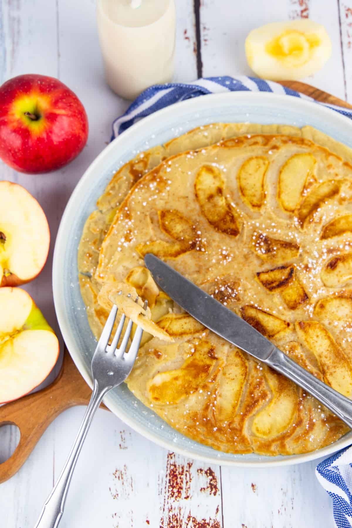 a plate with a German apple pancake with a fork with a piece of pancake
