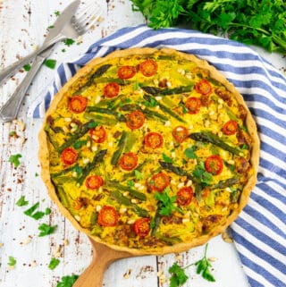 a vegan quiche on a wooden cutting board with parsley in the background