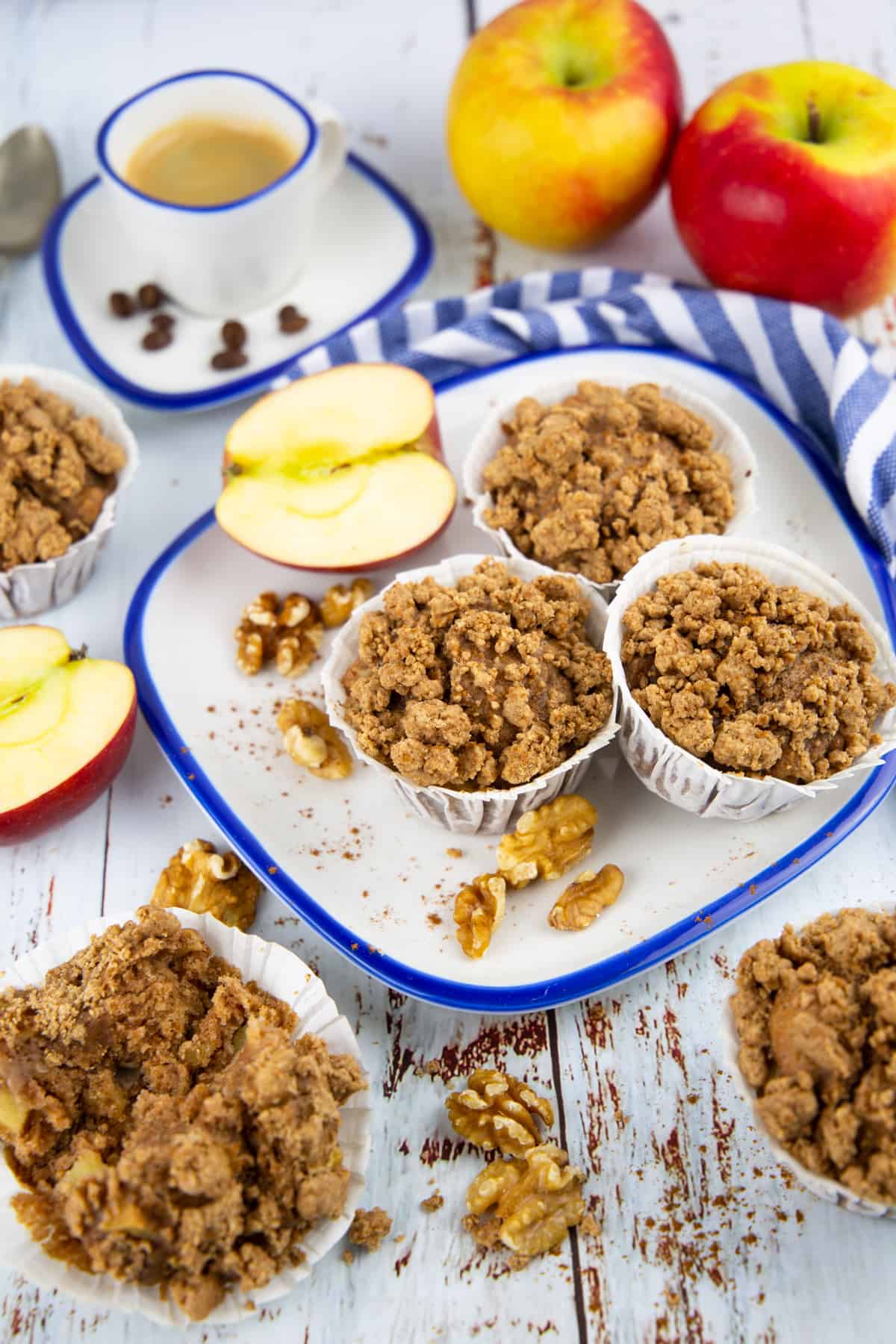 three apple cinnamon muffins on a plate with apples in the background