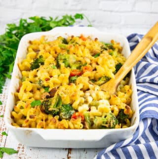 vegan pasta bake with broccoli and tomatoes in a white casserole dish