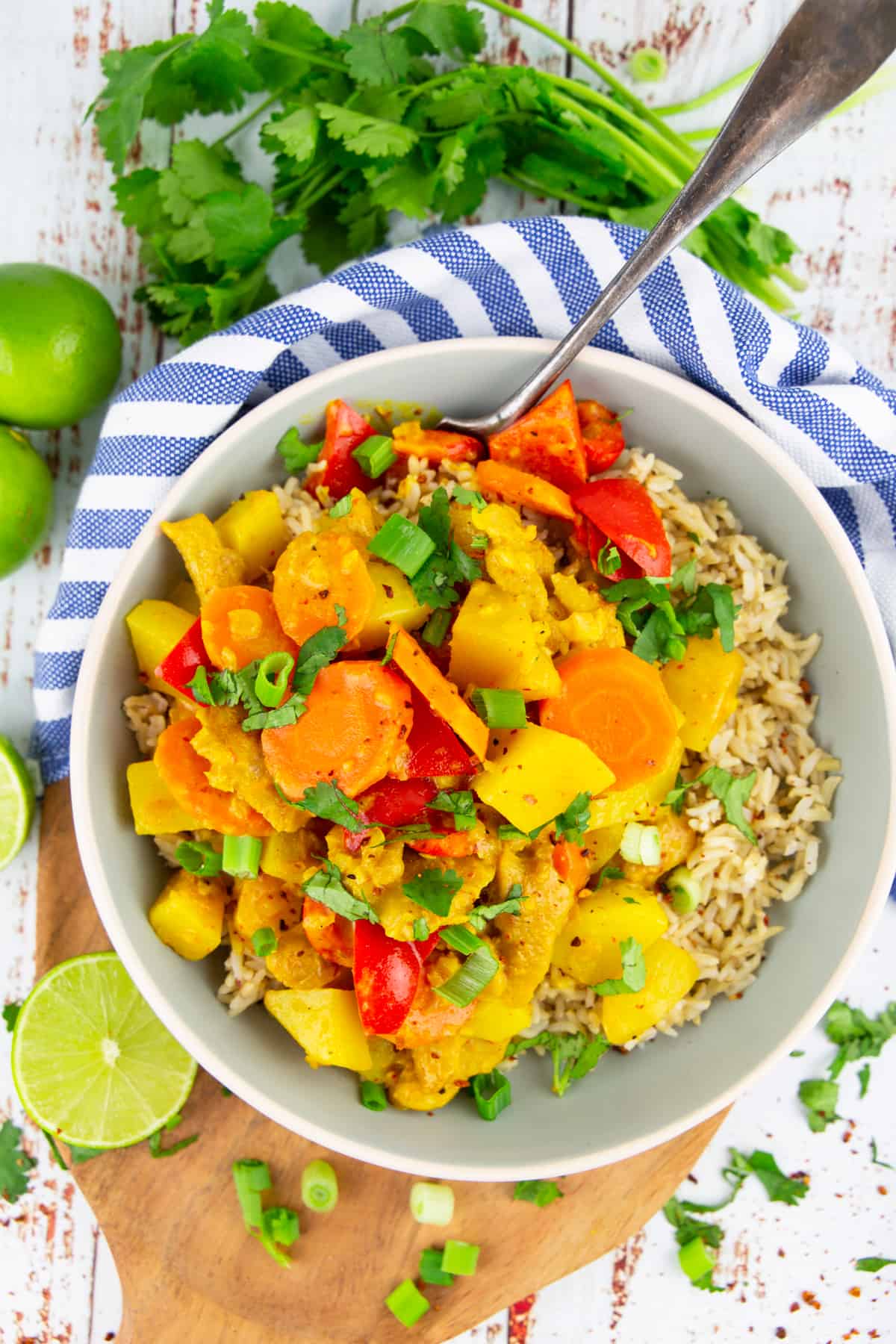 yellow curry with bell pepper and carrots over brown rice in a grey bowl 