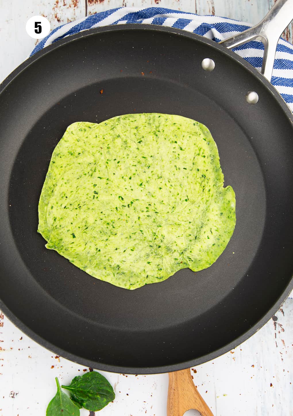a green tortilla with spinach in a ball pan on a wooden board 