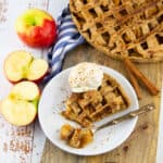 a slice of vegan apple pie on a white plate with vanilla ice cream and a fork