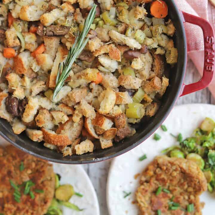 vegan stuffing in red pan with two white plates on the side