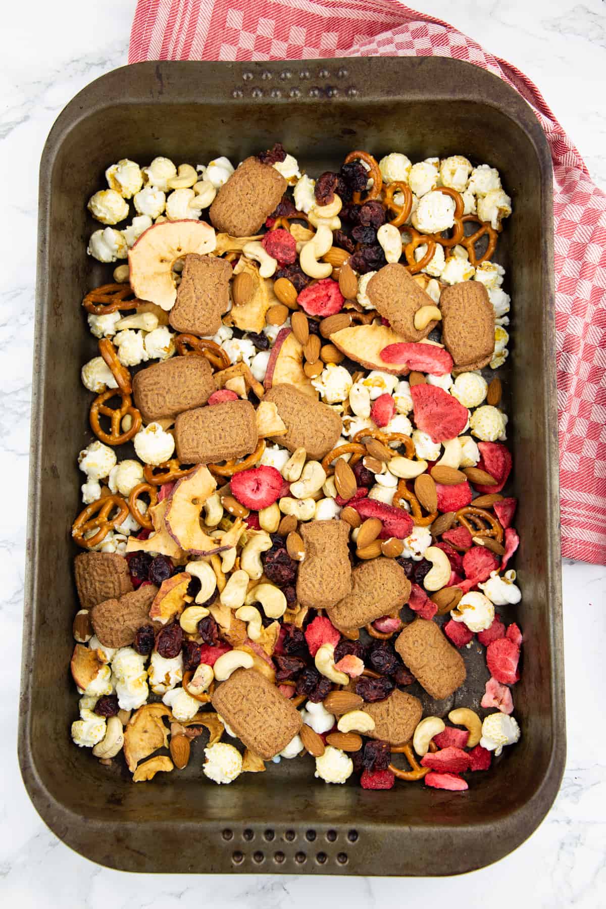 popcorn, specucools, dried strawberries, and snack pretzels on a sheet pan 