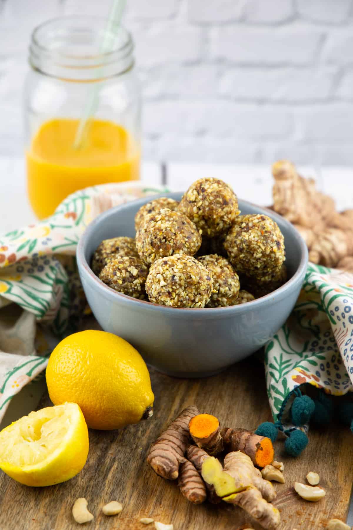 turmeric energy balls in a blue bowl with a glass of smoothie in the background 