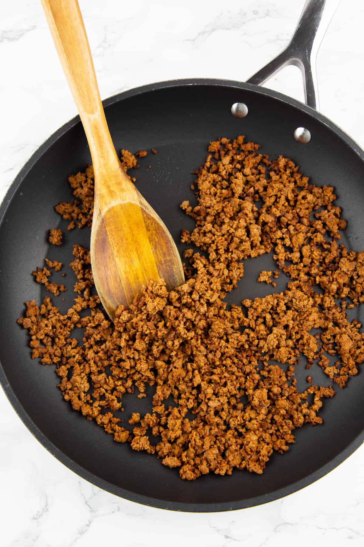 vegan ground meat in a black pan on a marble countertop 