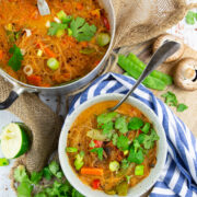 a bowl of glass noodle soup with a pot of soup in the background