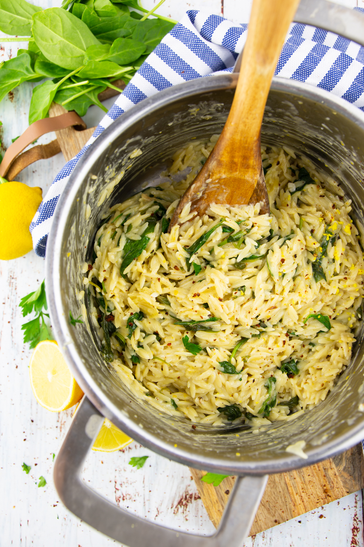 a pot with lemon orzo with spinach on a white wooden board 