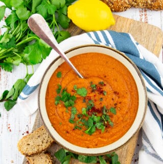 a bowl of Turkish lentil soup on a wooden board with parsley in the background