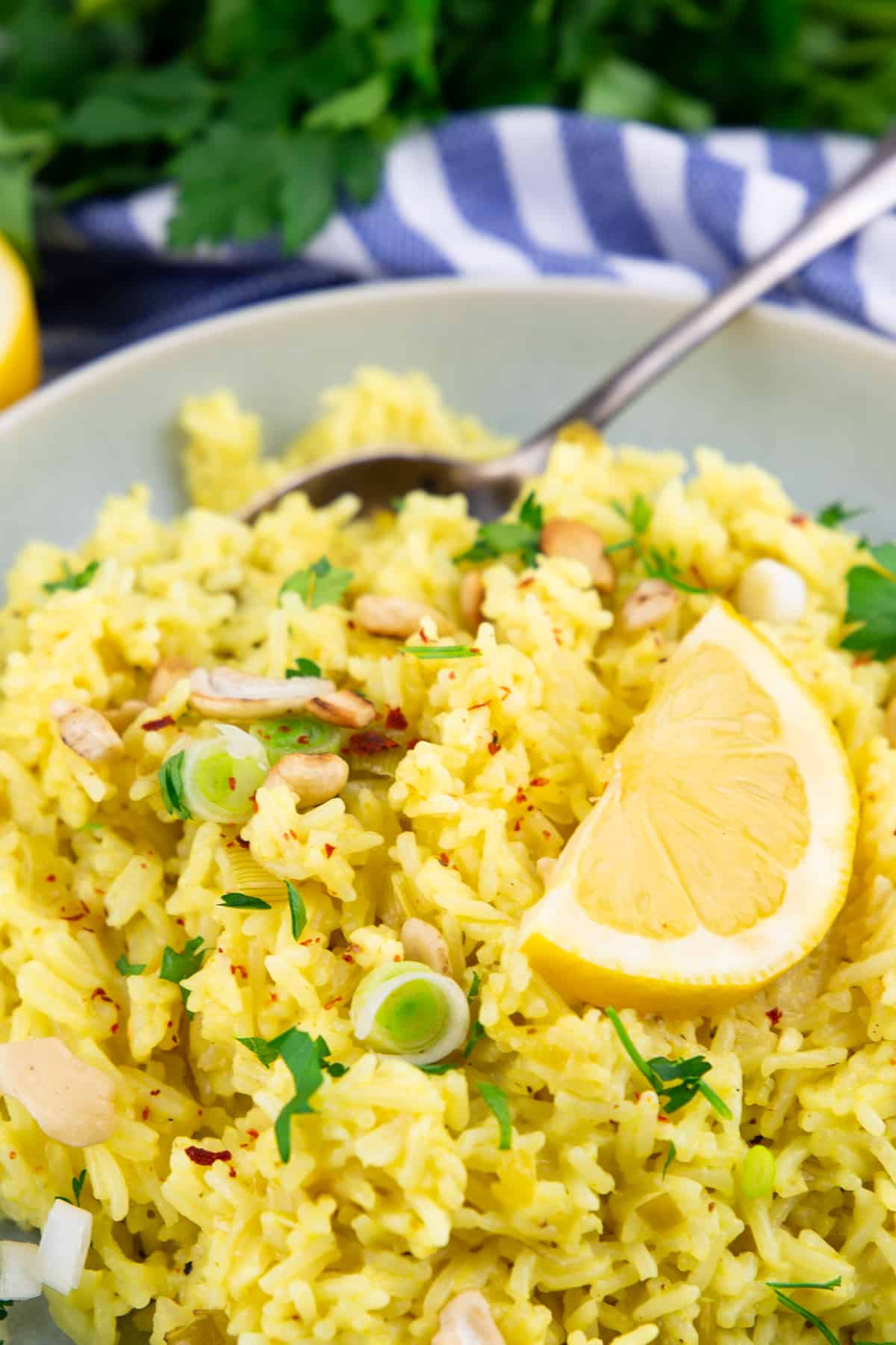 rice topped with green onions and a slice of lemon in a grey bowl 