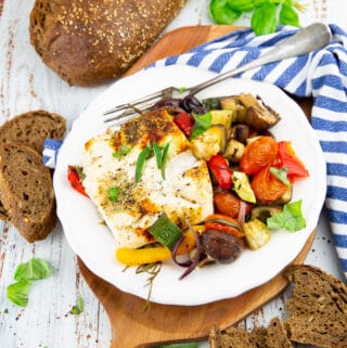 roasted vegetables with baked vegan feta on a white plate with a fork