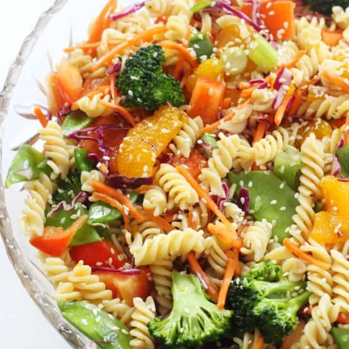 an Asian pasta salad with broccoli and carrots in a glass bowl