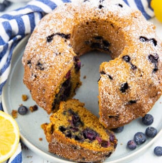 a blueberry pound cake on a grey plate with lemons in the background