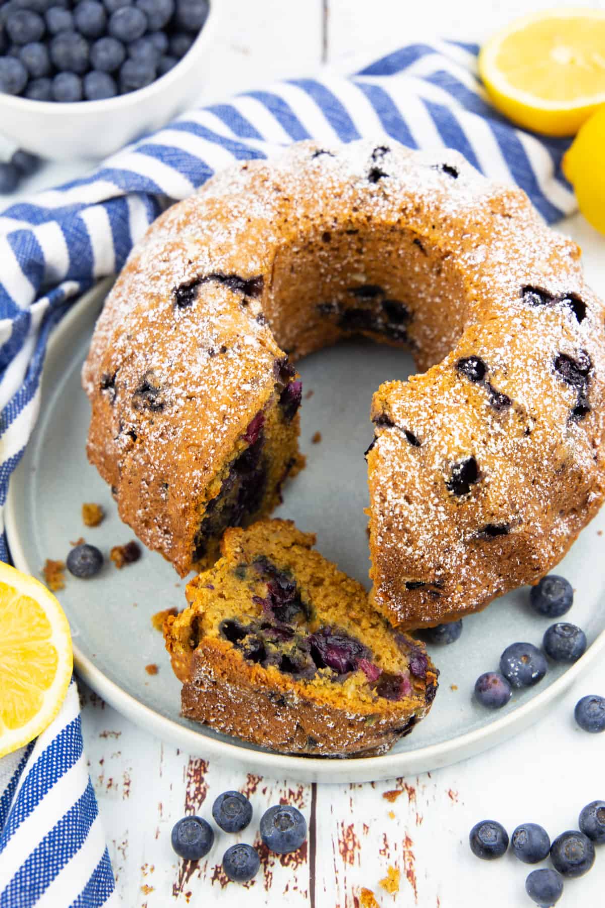 a blueberry pound cake on a grey plate with lemons in the background 