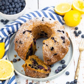 a blueberry pound cake on a grey plate with lemons in the background