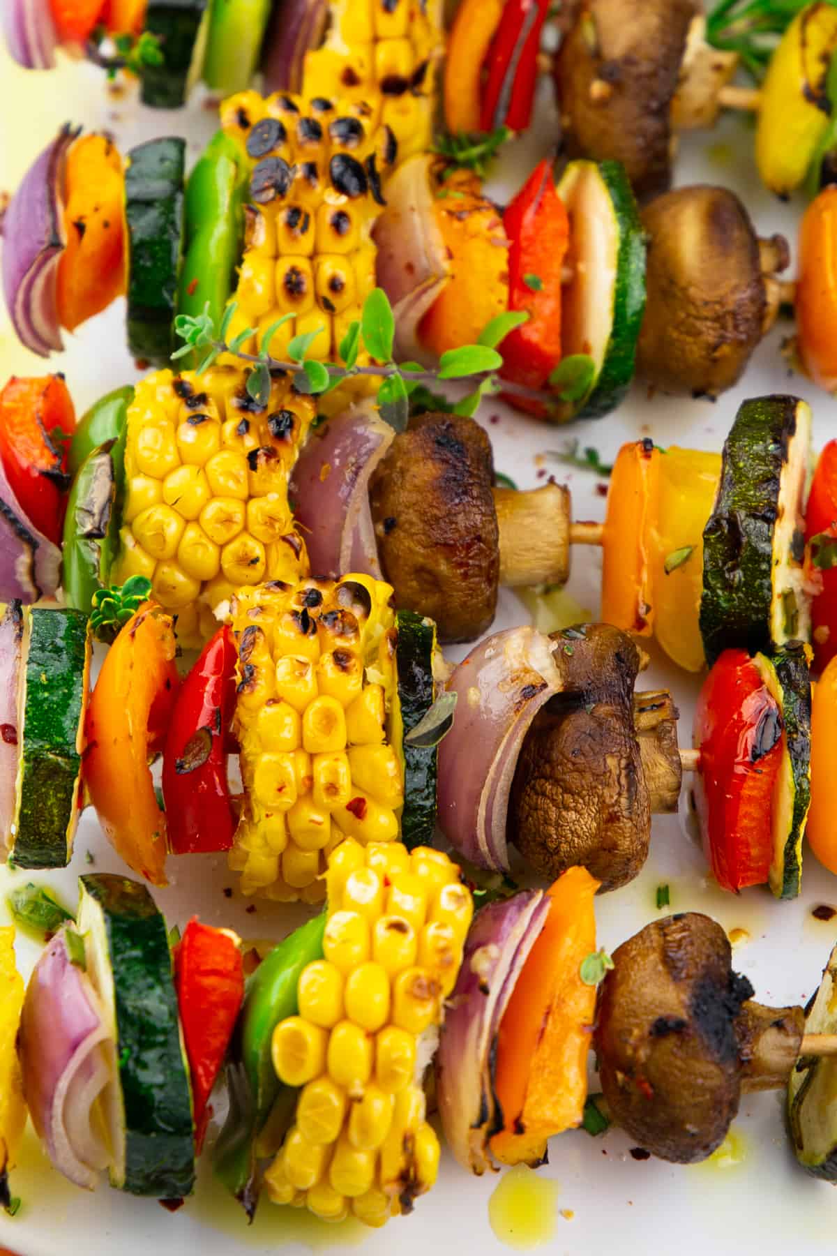 vegetable skewers with corn and mushrooms on a white plate 