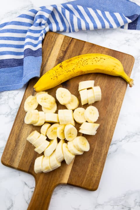 banana slices on a wooden chopping board on a marble countertop