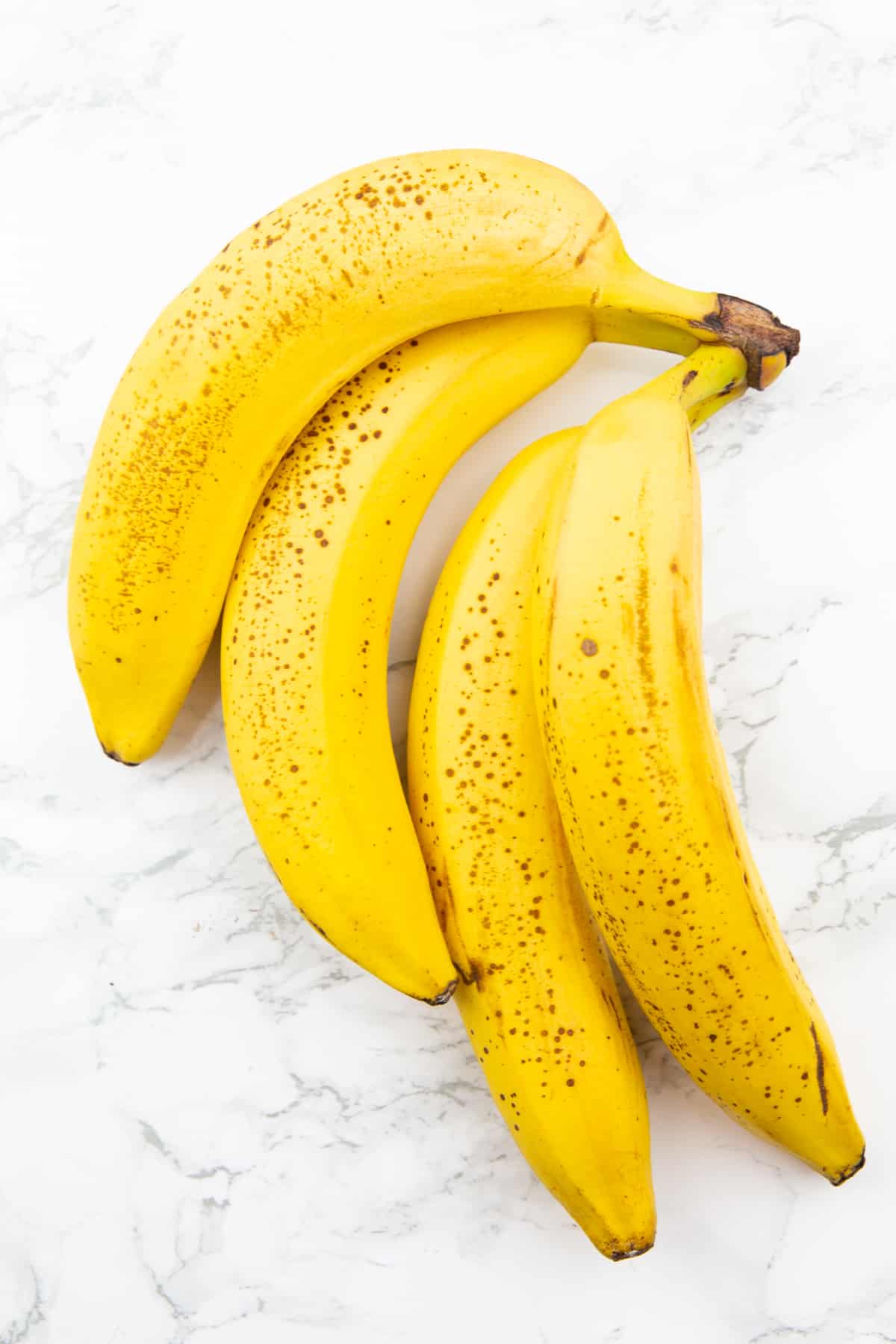 four ripe bananas on a marble countertop 