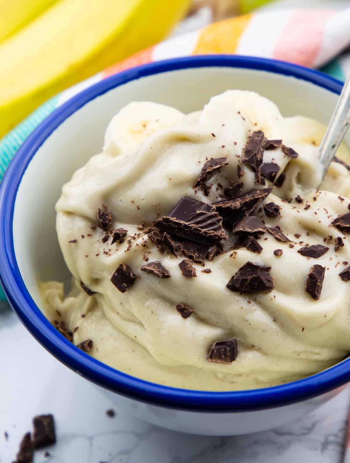 frozen banana ice cream topped with chopped dark chocolate in a blue bowl 