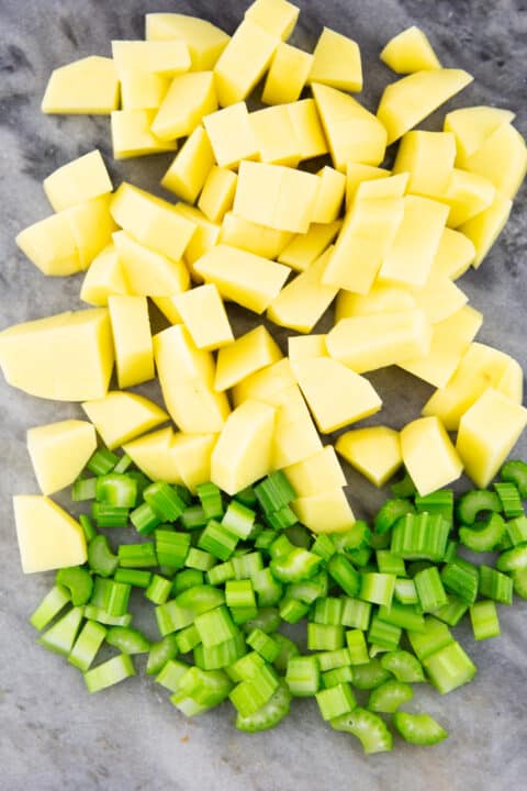 cubed potatoes and celery on a marble chopping board