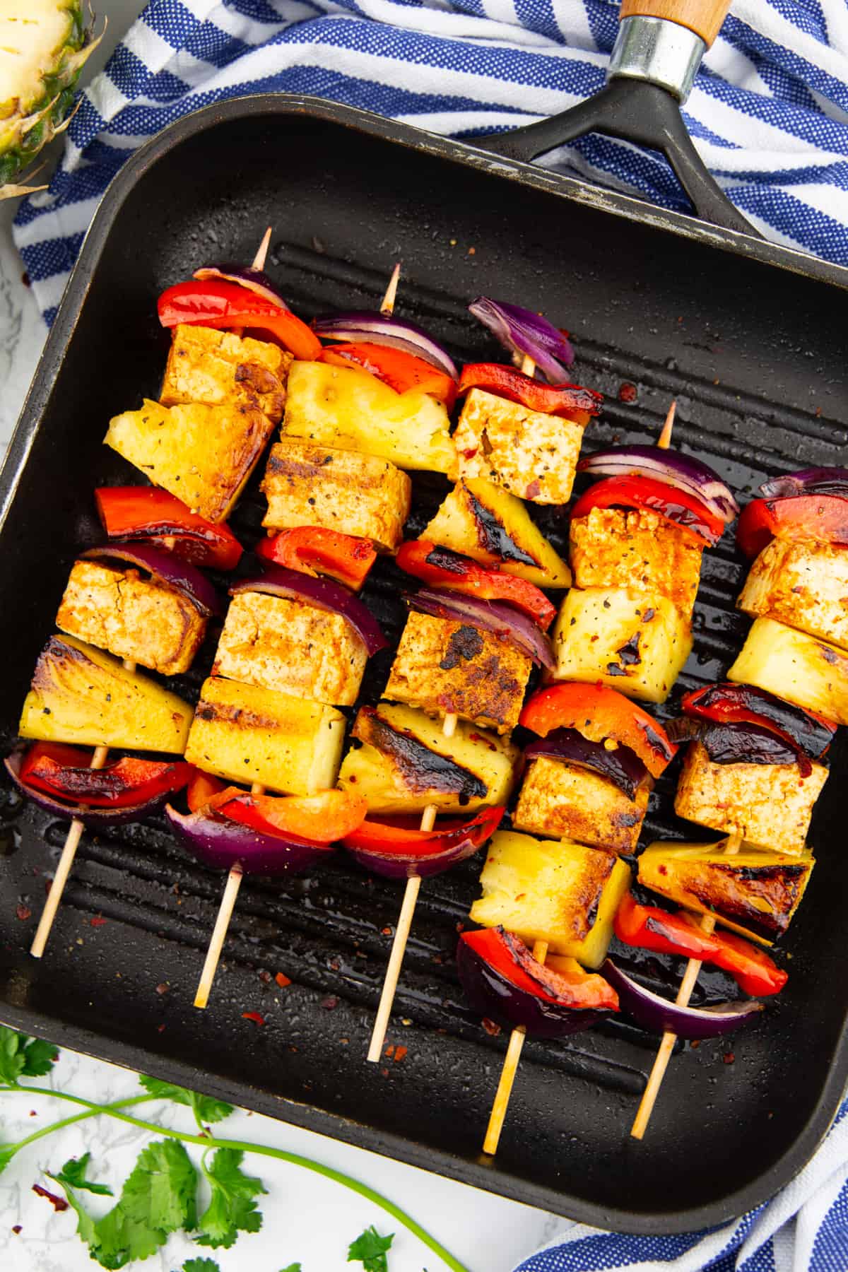five tofu skewers with pineapple and red bell pepper in a grilling pan