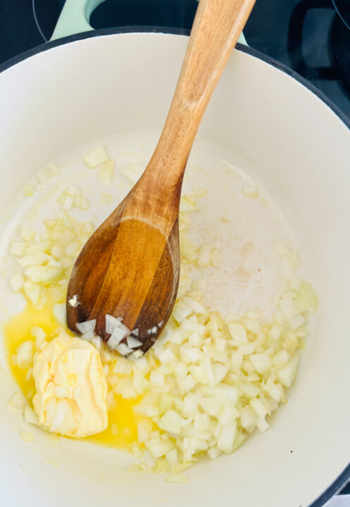 sautéd onion and garlic in a white pot with vegan butter 