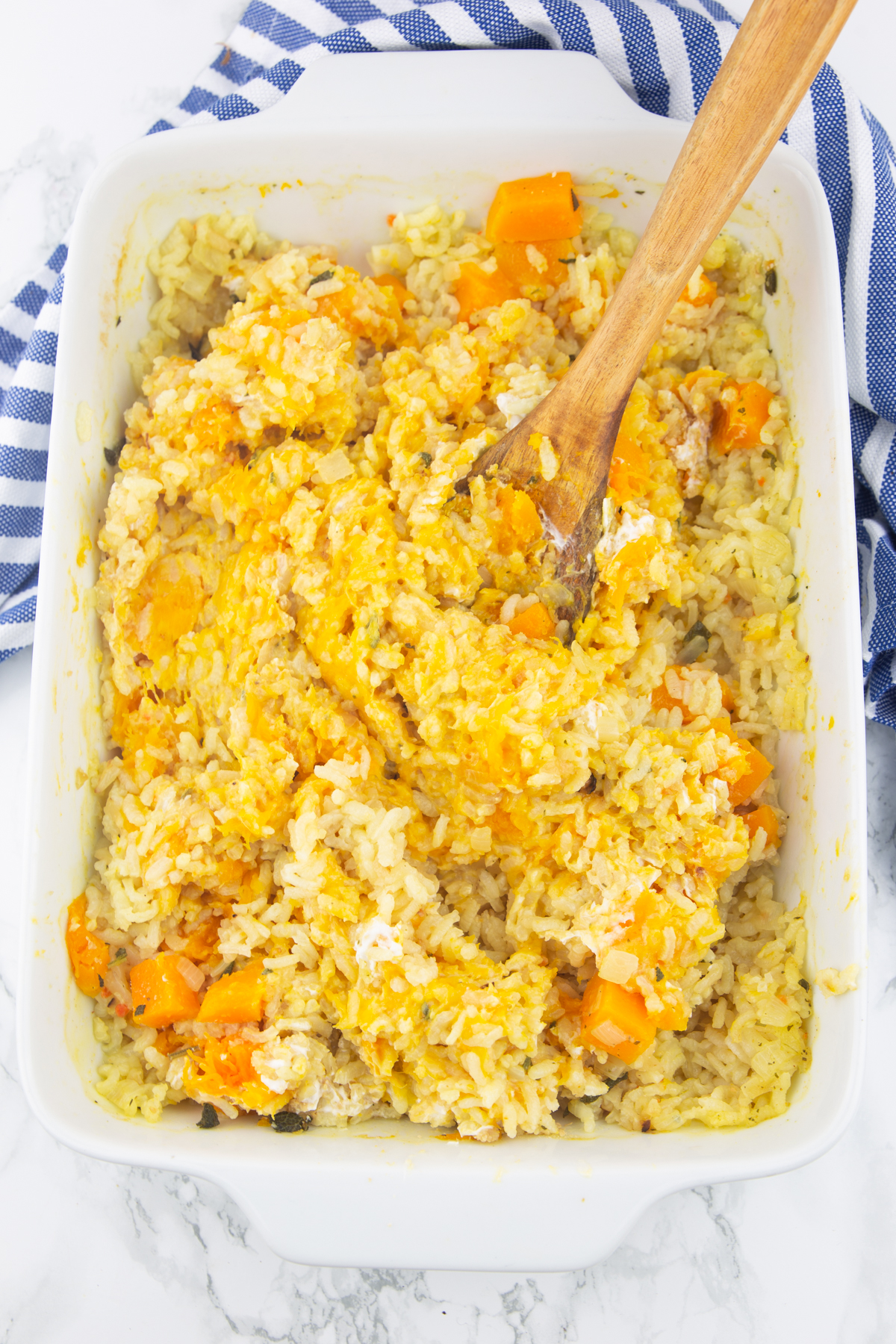 oven-baked risotto with butternut squash in a white casserole dish with a wooden spoon