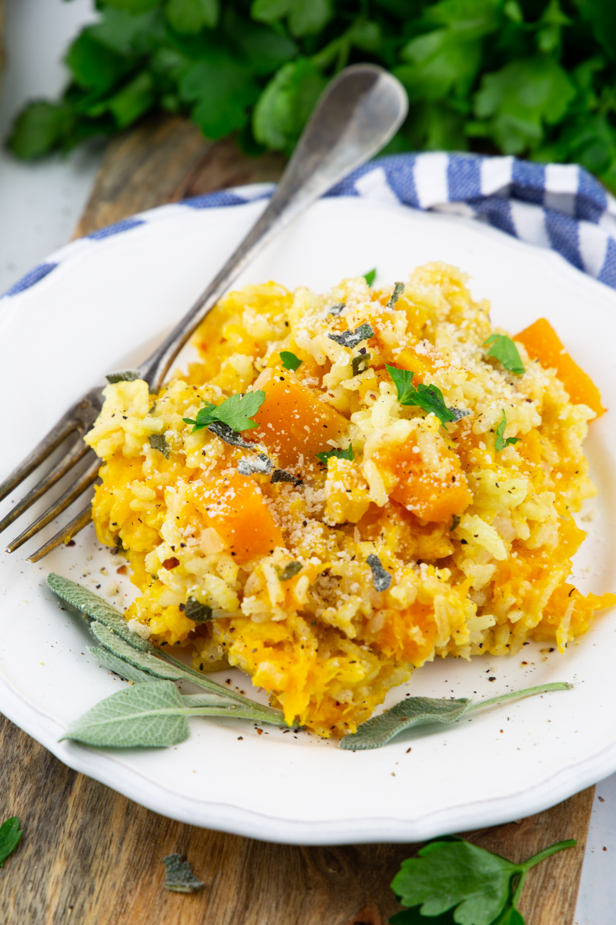 a white plate with butternut squash risotto with fresh sage and a fork 