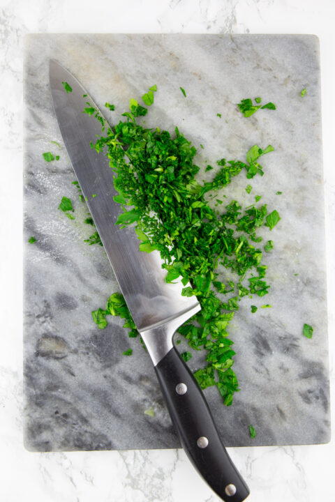 finely chopped parsley with a knife on a chopping board