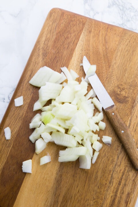 finely chopped onion on a wooden chopping board 