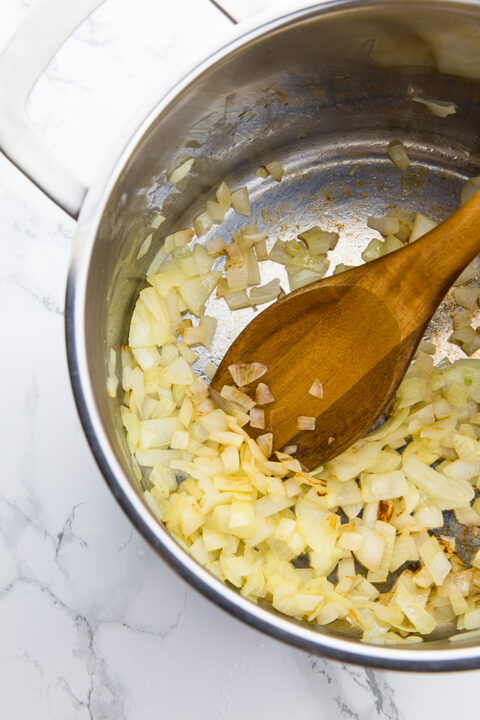 sautéd onion in a pot with a wooden spoon 