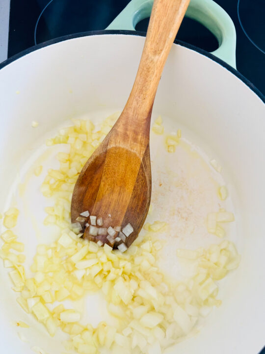 sautéd onion in a large pot with a wooden spoon