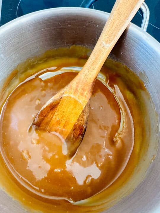a pot with vegan caramel sauce with a wooden spoon 