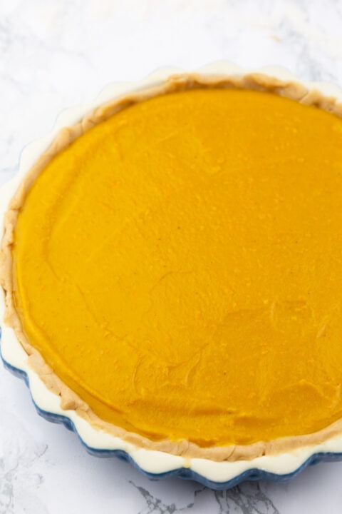 a vegan pumpkin pie before baking on a marble countertop 