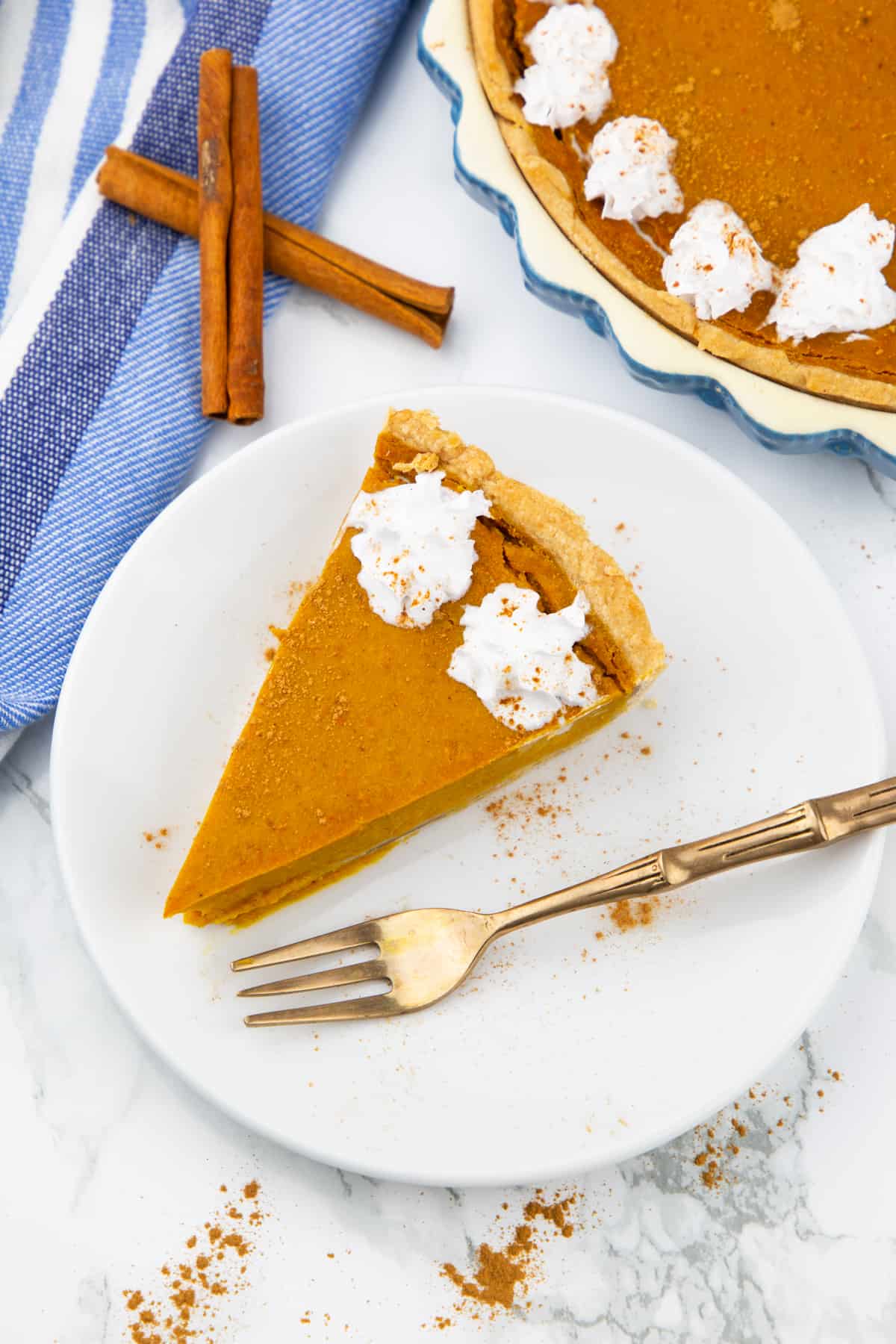 a slice of vegan pumpkin pie on a white plate with a fork on the side 