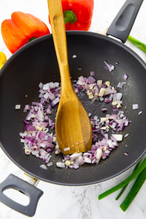 sautéd onion in a black pan with a wooden spoon