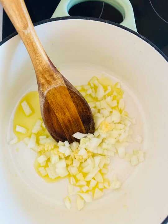 sautéd onion in a white pot with a wooden spoon 