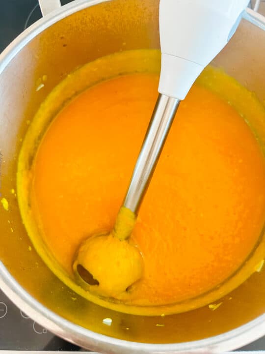freshly blended sweet potato soup in a pot with an immersion blender 