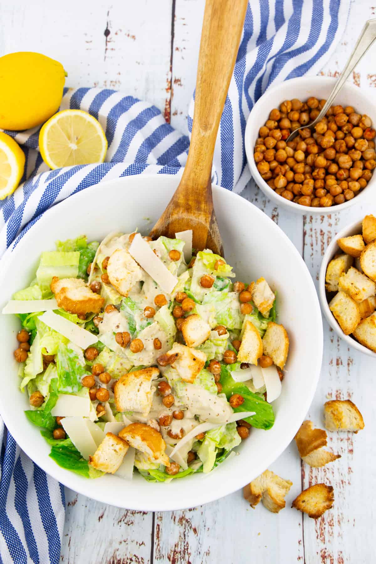 a white bowl with vegan Caesar salad with croutons and roasted chickpeas on a white wooden board 