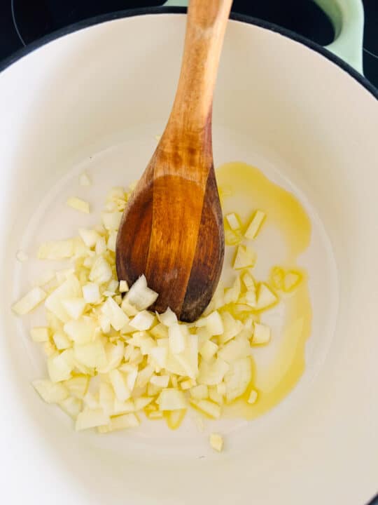 sautéed onion in a white pot with a wooden spoon 