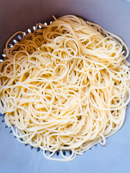 cooked spaghetti in a grey colander 