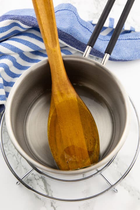 melted coconut oil in a small pot with a wooden spoon 
