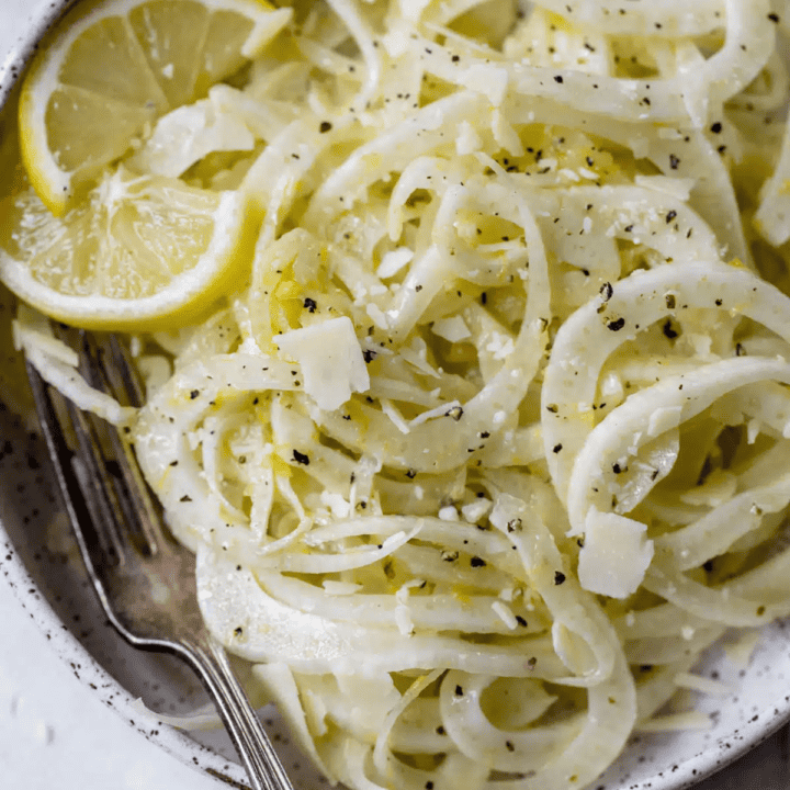 a grey bowl with fennel salad with lemon slices and a fork