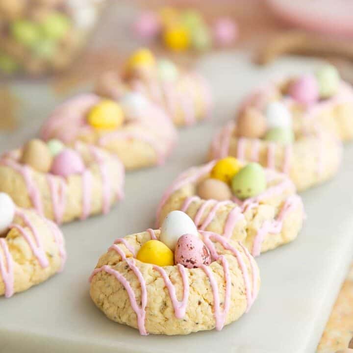 eight vegan Easter cookies in form of a little with with mini eggs on a white marble board