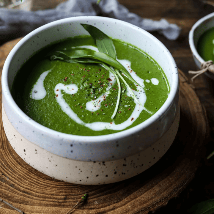 a beige bowl with creamy vegan wild garlic soup on a wooden board