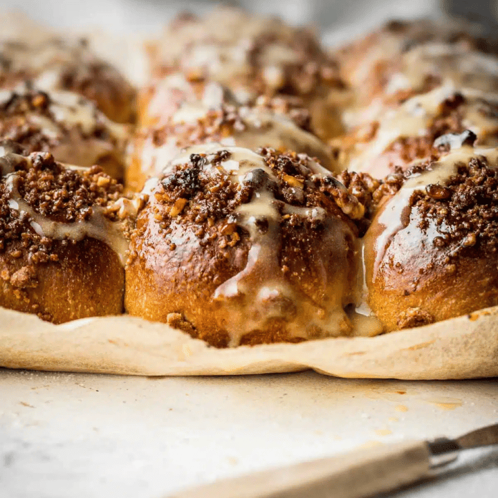 sticky rolls with walnut streusel on parchment paper with a knife on the side