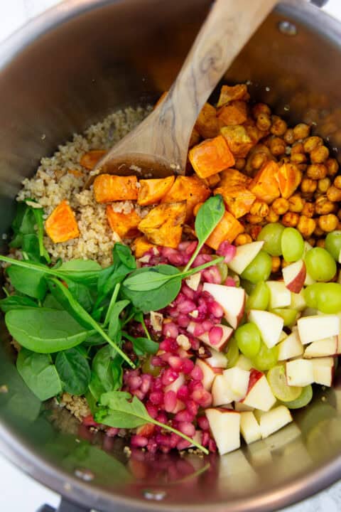 the ingredients for this fall quinoa salad in a bowl with a wooden spoon